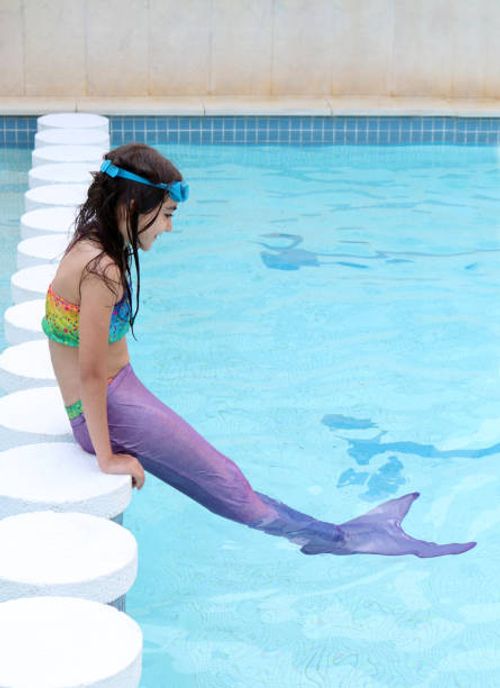 Dívka s ocasem mořské panny sedící u bazénu